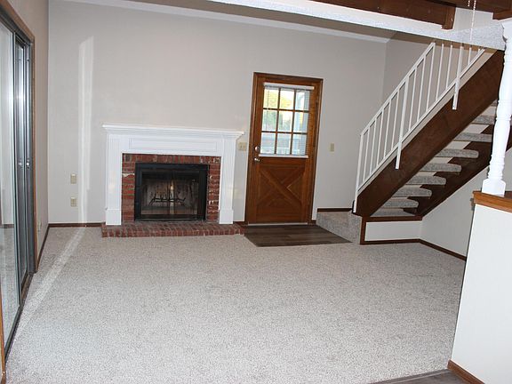 Living room with new carpet and wood-burning fireplace.