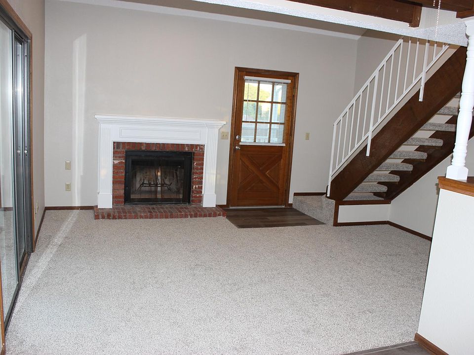 Living room with new carpet and wood-burning fireplace.