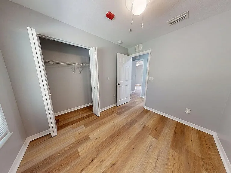 Bright bedroom with sleek hardwood floors and a spacious closet, perfect for modern living.