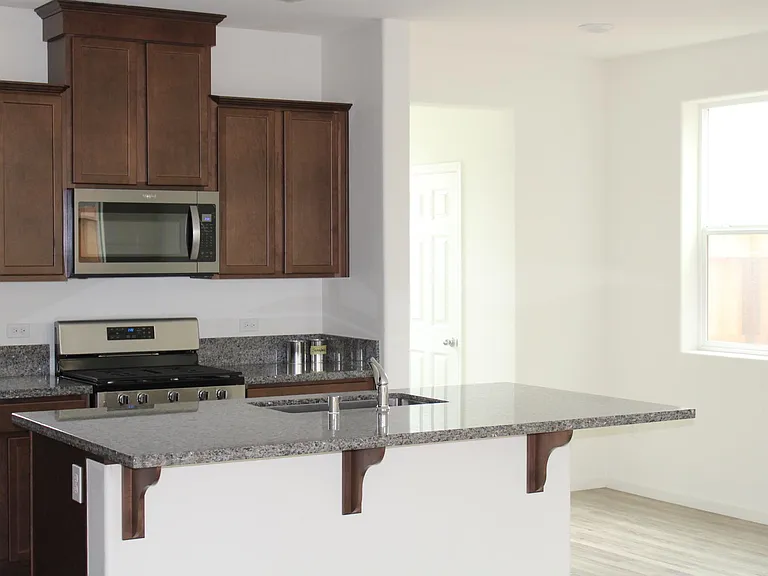 sink in island, overhang for roomy bar stool seating.