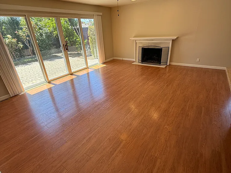living room/family room, directly off dining room and kitchen. Shows gas fireplace, ceiling fan and light, clean floors, floor boards and extra large slider to backyard