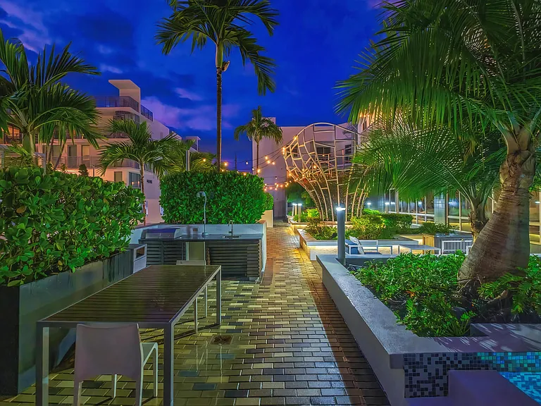 Palm-Lined Courtyard with Outdoor Kitchen and Dining Area at South of Atlantic