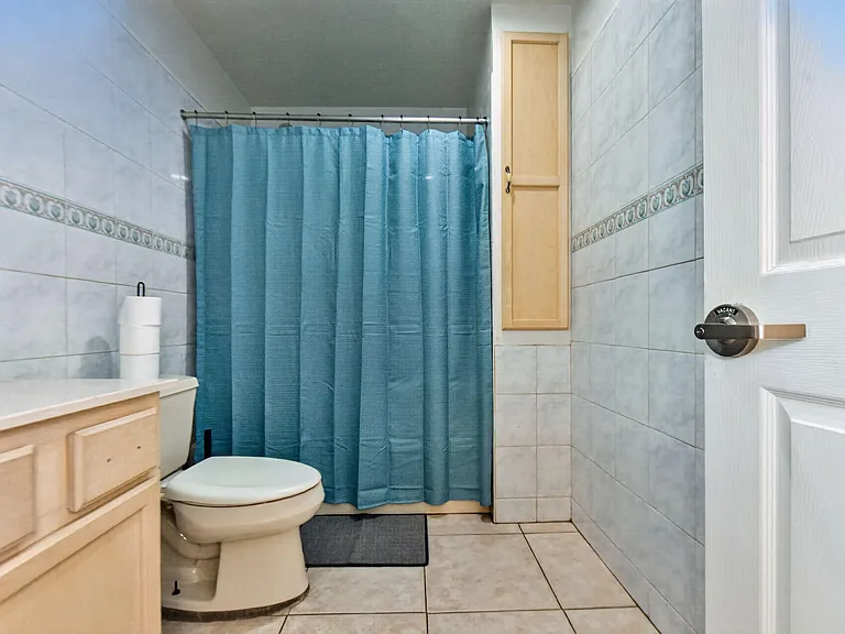 Full bathroom with tiled walls and flooring, a vanity with storage, and a shower/tub combo with curtain.