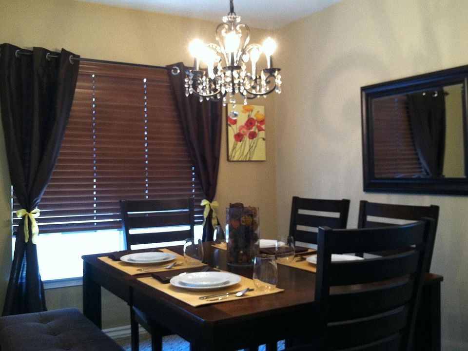 Dining room (across from kitchen) has beige paint and a custom chandelier