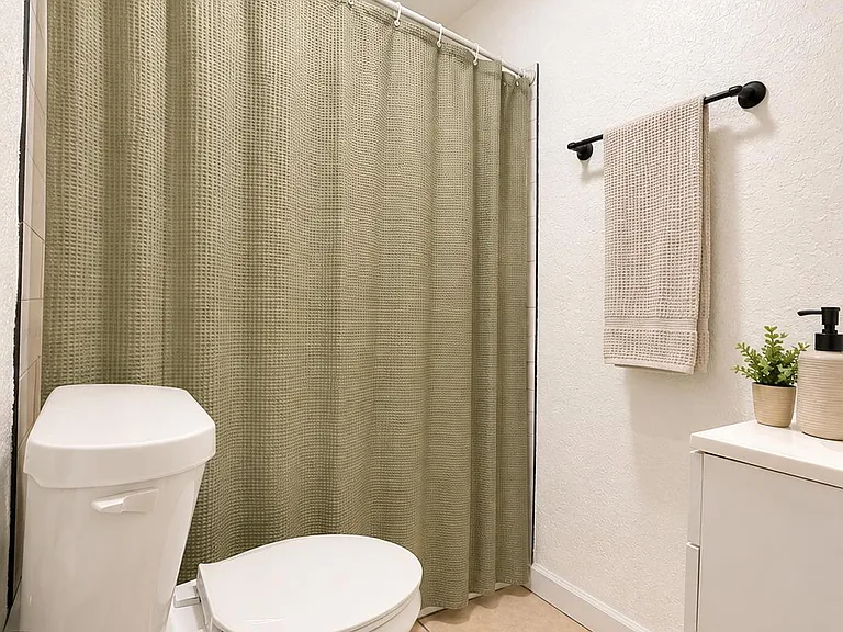 Clean full bathroom with tub/shower combo, tiled flooring, and a vanity counter for everyday storage and convenience.