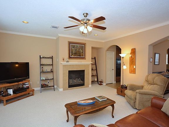 Second view of the living area with crown molding, berber carpet and neutral paint color.