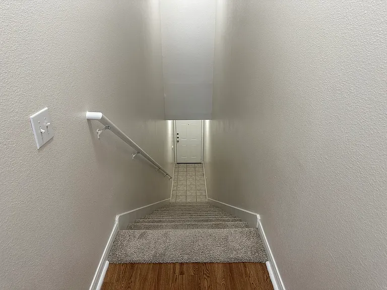 Bright and inviting staircase with elegant carpet and wood-style flooring leading to a spacious entryway. Bright and inviting staircase with elegant carpet and wood-style flooring leading to a spacious entryway.