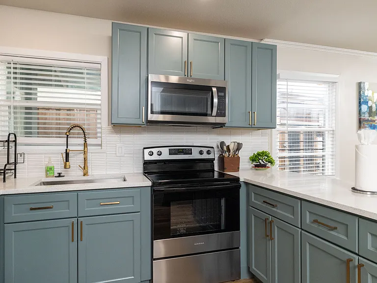 Bright, modern kitchen with stainless appliances, teal cabinets, and a spacious island_perfect for cooking, gathering, and enjoying a warm, stylish space.