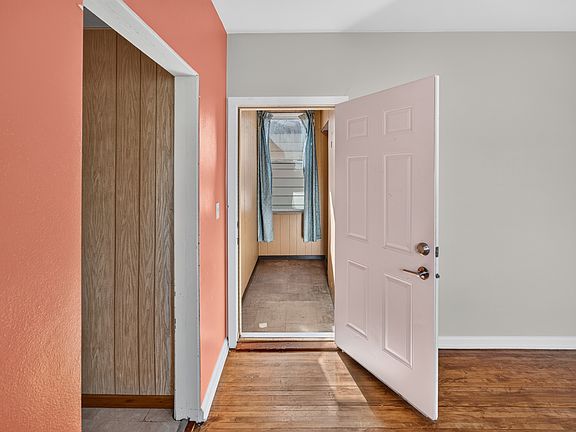 Interior hall and doorway transition showcasing original hardwood floors and bright natural light.