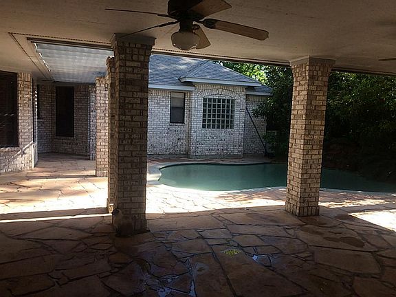 Outdoor patio with stone flooring and pool. Indoor wet bar leads to the pool for entertaining