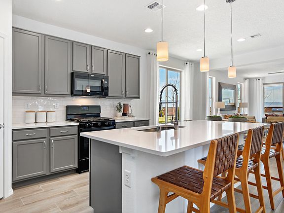 The Hewitt kitchen featuring stylish grey cabinets, marble countertops, and sleek black appliances.