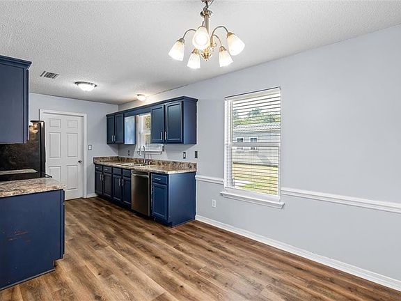 Kitchen with dark hardwood / wood-style floors, black appliances, sink, and blue cabinets