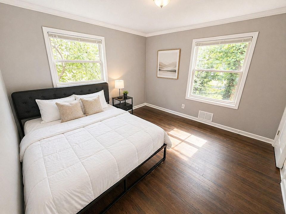 Spacious bedroom with two large windows, hardwood floors, and room for a queen bed with nightstand setup.