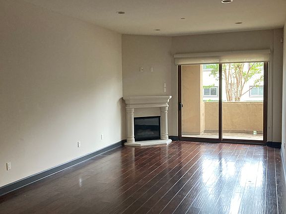 Gas fireplace, wood floors, roller shades, dimmable lights, green view.