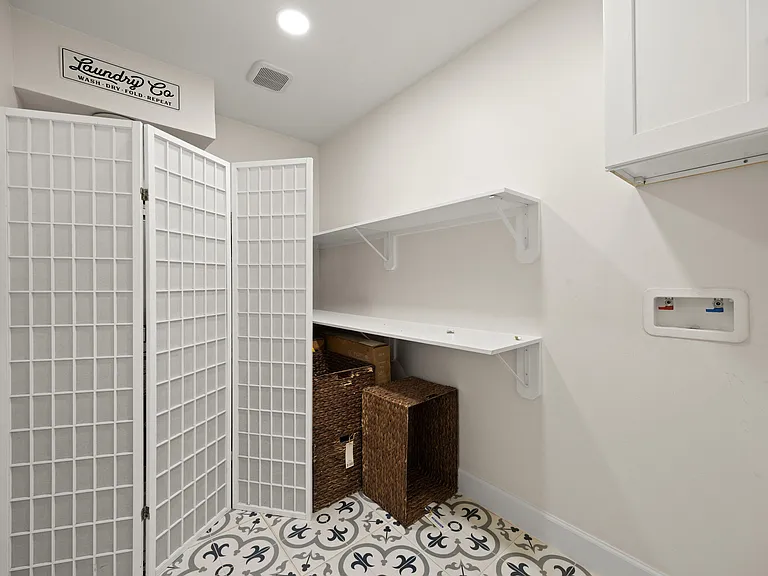 Dedicated laundry area with folding counter, wall shelving, and utility hookups, plus space for hampers and supplies.