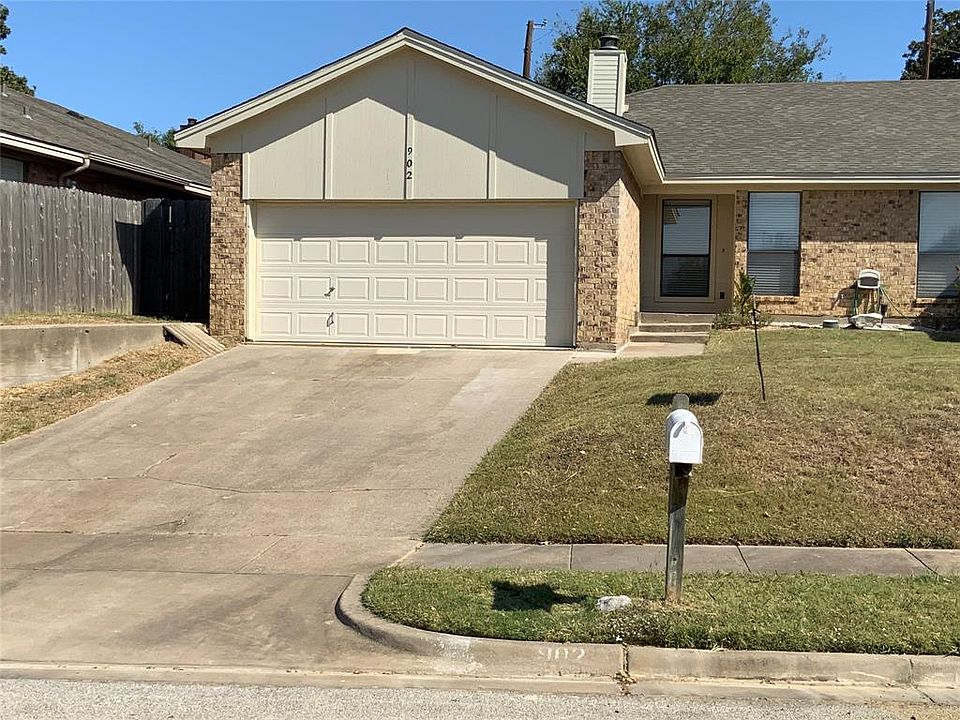 Single story home with driveway, fence, a garage, brick siding, and a chimney