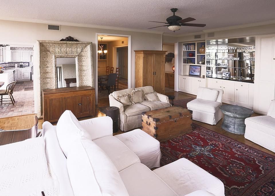 SPACOUS LIVING ROOM WITH BUILT-IN BOOKSHELVES AND MIRRORED BAR.