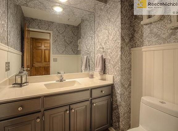 The darling Half Bath on the first floor has grey enamel cabinets, bead board and a large vanity.