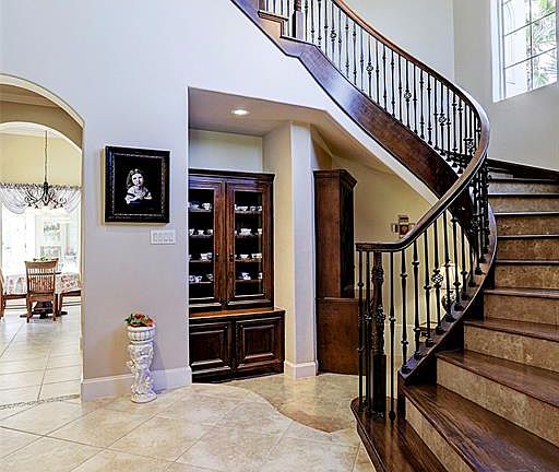 As you enter through the beveled glass paned double doors you will see the stunning front stairwell with wooden treds, travertine risers and decorative wrought iron spindles. Underneath the stairs is a wine grotto and built in china cabinet. Lots of 