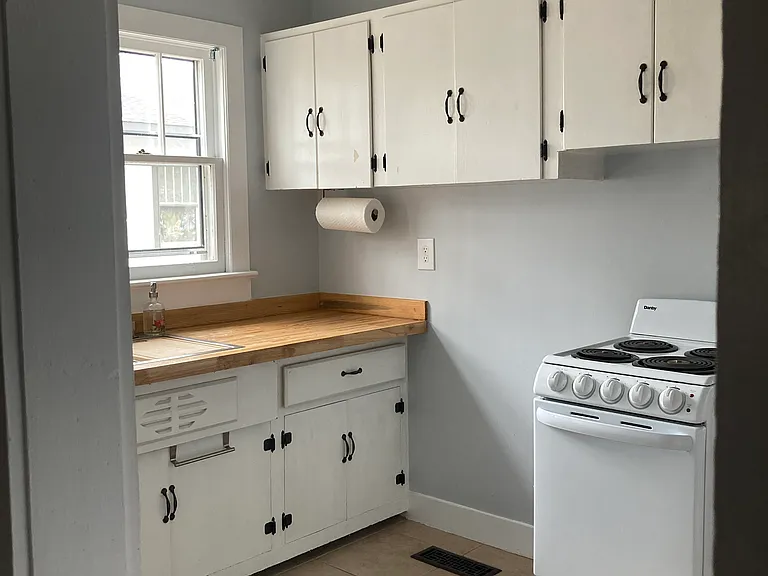 Kitchen- view of cabinets, stove and sink area.