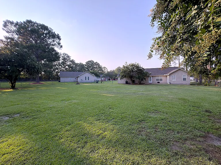 Expansive fenced backyard shaded by mature trees_lawn care included