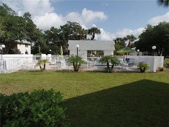 Community pool area with lounge chairs and umbrella tables.