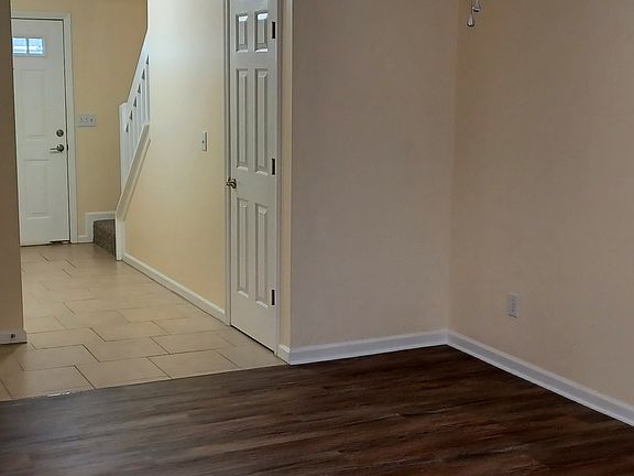 View from living room to front door. Water heater and storage room door on right under stairs