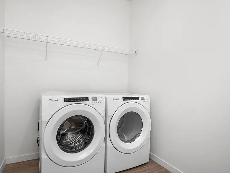 Modern laundry room featuring energy-efficient washer and dryer with sleek shelving above. Modern laundry room featuring energy-efficient washer and dryer with sleek shelving above.