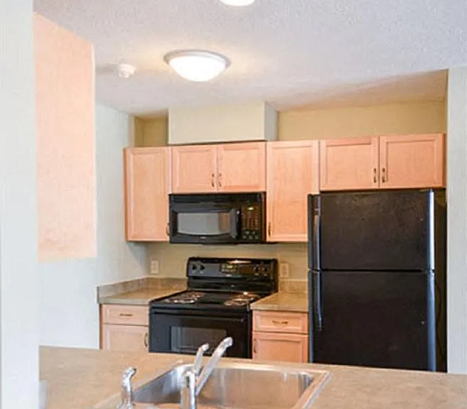 View of well equipped kitchen with black appliances, wood cabinetry, and breakfast bar
