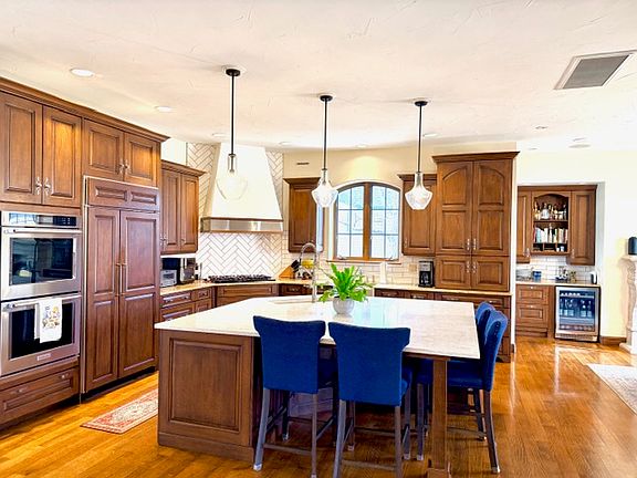 Chef's kitchen with expansive island, double oven, two dishwashers, two sinks, sub-zero fridge, and microwave inside cabinetry.