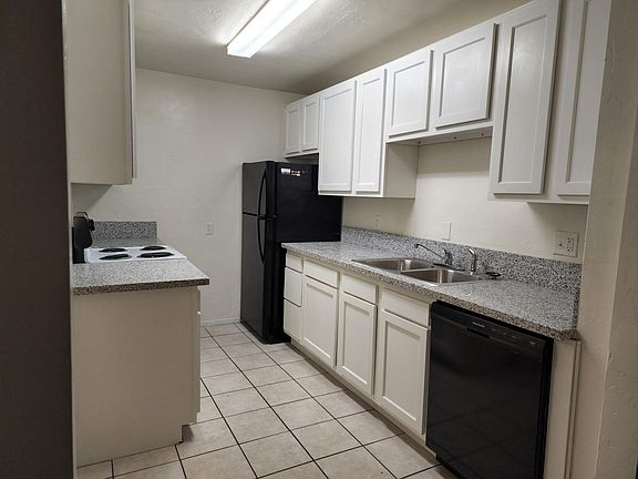 Bright kitchen with 2 fridges, granite countertops, and door outside (not pictured)