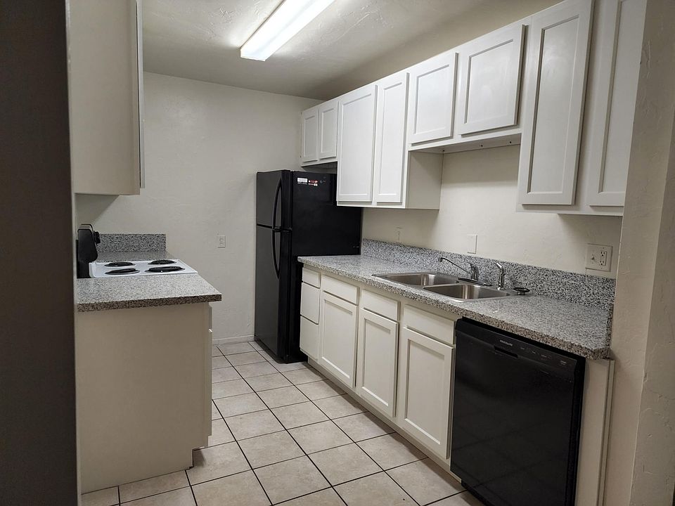 Bright kitchen with 2 fridges, granite countertops, and door outside (not pictured)