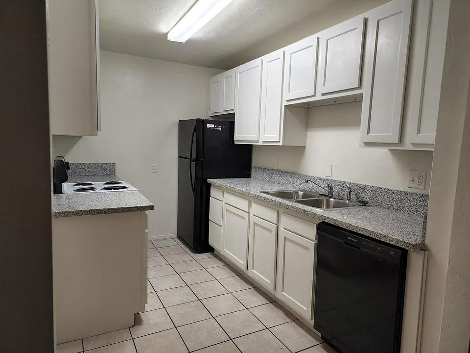Bright kitchen with 2 fridges, granite countertops, and door outside (not pictured)