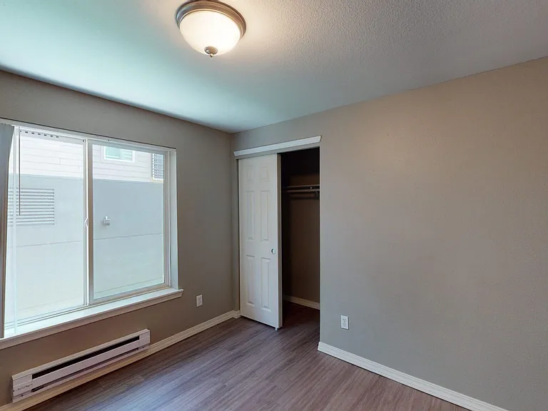 Spacious apartment bedroom with wood-style or plush carpet flooring.
