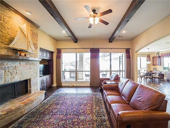 Beautiful family room with custom floor to ceiling stone fireplace, beam ceiling, built-ins and wall of windows