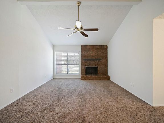 Living room with a wood burning brick surround fireplace. Large window with new blinds throughout the entire house.
