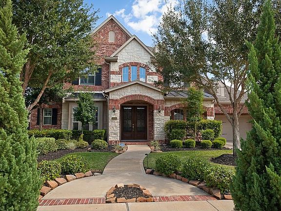 Cypress trees and lush landscaping frame the lovely walkway up to this beautiful home. Matching brick insets are blended throughout the pathway to tastefully compliment the home's exterior.