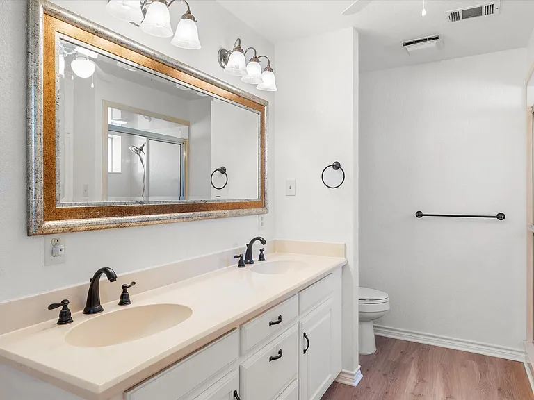 Bathroom featuring a dual vanity with a light-toned countertop, two integrated sinks, and dark bronze-finish faucets