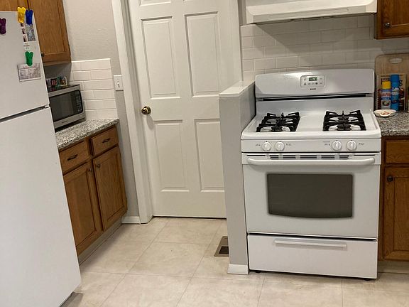 Part of kitchen showing gas stove, fridge, door to laundry room leading to backyard