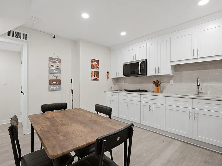 Eat-in kitchen with extensive cabinetry, subway-tile backsplash, sink, and microwave, plus space for a dining table.