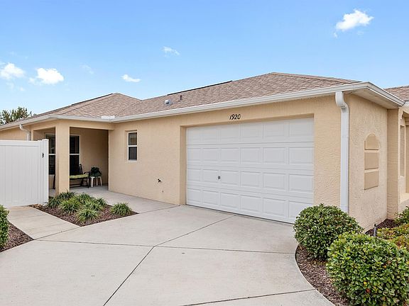 Front of house showing sitting porch with rocking chair, private driveway, and garage for one medium sized cart + a golf cart. Additional parking for guests available around the corner.