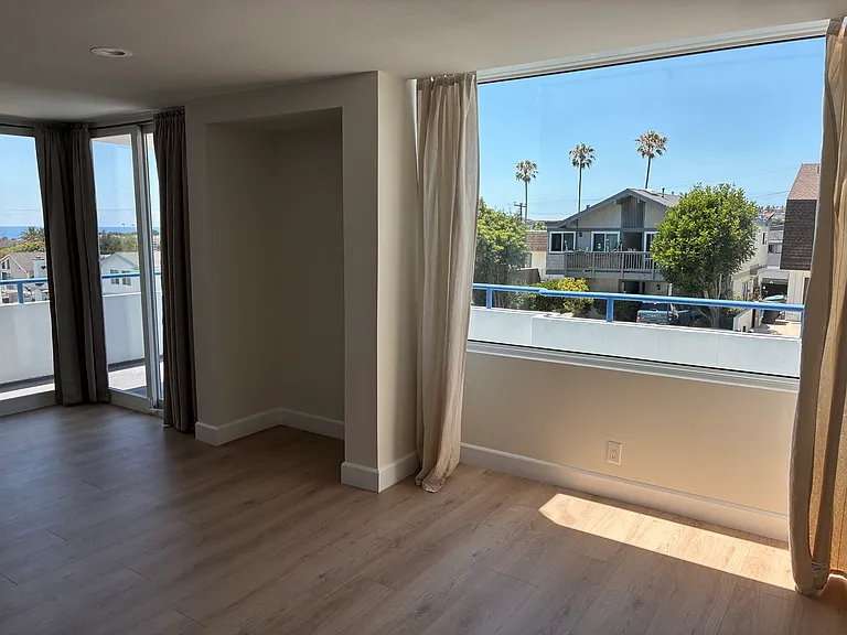 Sun drenched living area with large single pane window and dual patio doors leading to wrap around balcony.