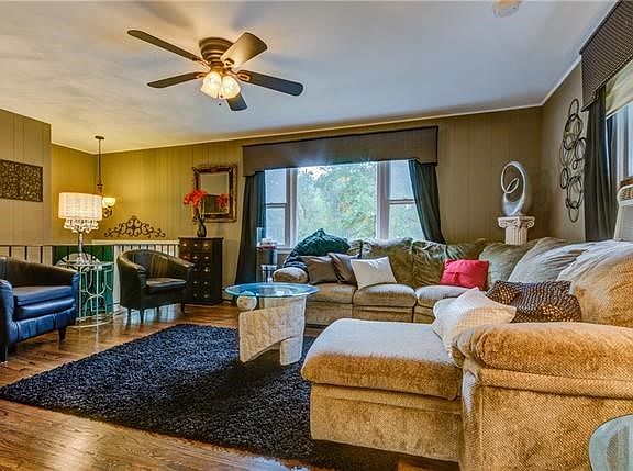 View of living room from dining room.  Newly refinished Hardwood Flooring and ceiling fan.