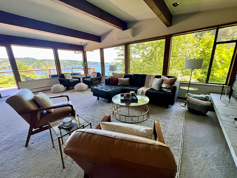 Upper level living room with wall of windows exposed solid wood beams with heat pump with AC and heating..