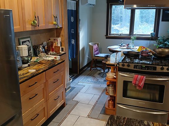 Newly remodeled Kitchen with custom alder cabinets, granite counter tops, tile floors leading into dining area, and pantry.