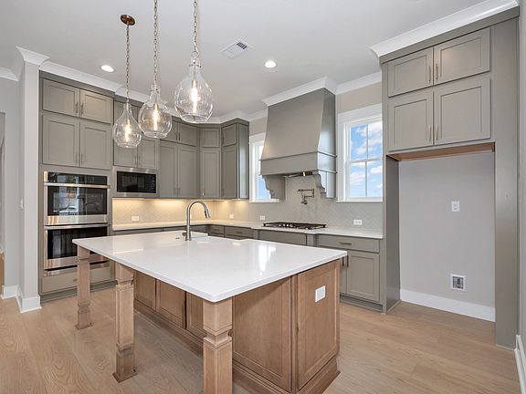 Kitchen with large island, pendant lighting, custom cabinets, and built-in oven and cooktop