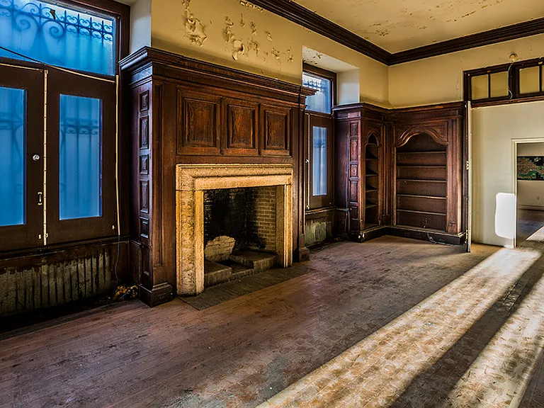 Before: Cigar lounge with wood-burning fireplace surrounded by wood paneled walls and built-in bookshelves