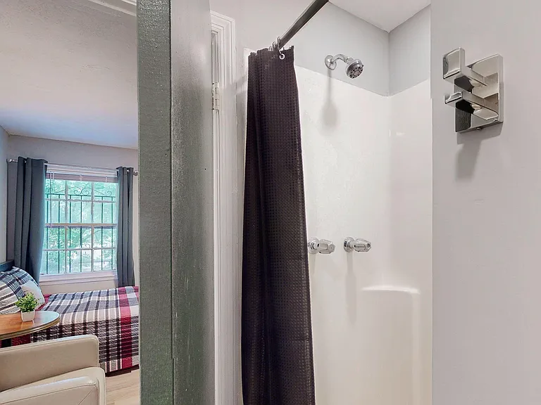 Tub/shower combo with chrome fixtures and a shower curtain in a simple, easy-to-maintain bath space.