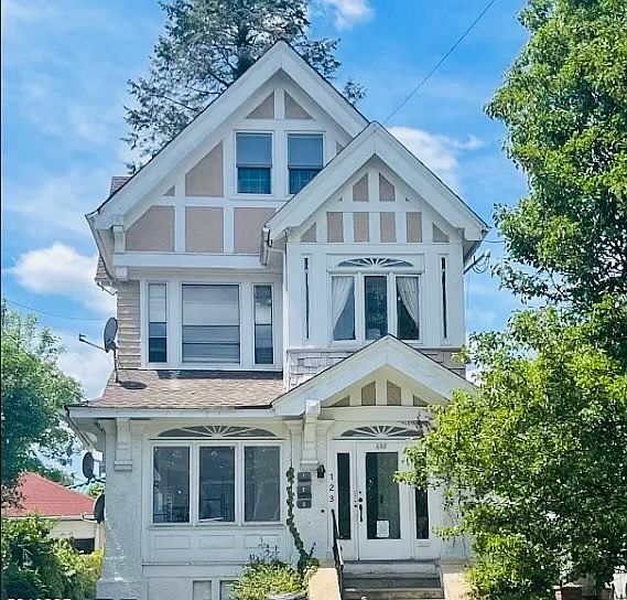 The inviting exterior of this beautifully renovated three-unit home features a charming front patio and private entrances for each unit, offering both warmth and privacy.