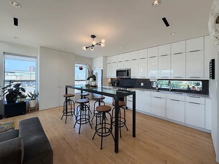 The kitchen features sleek white modern cabinetry and quartz countertops.
